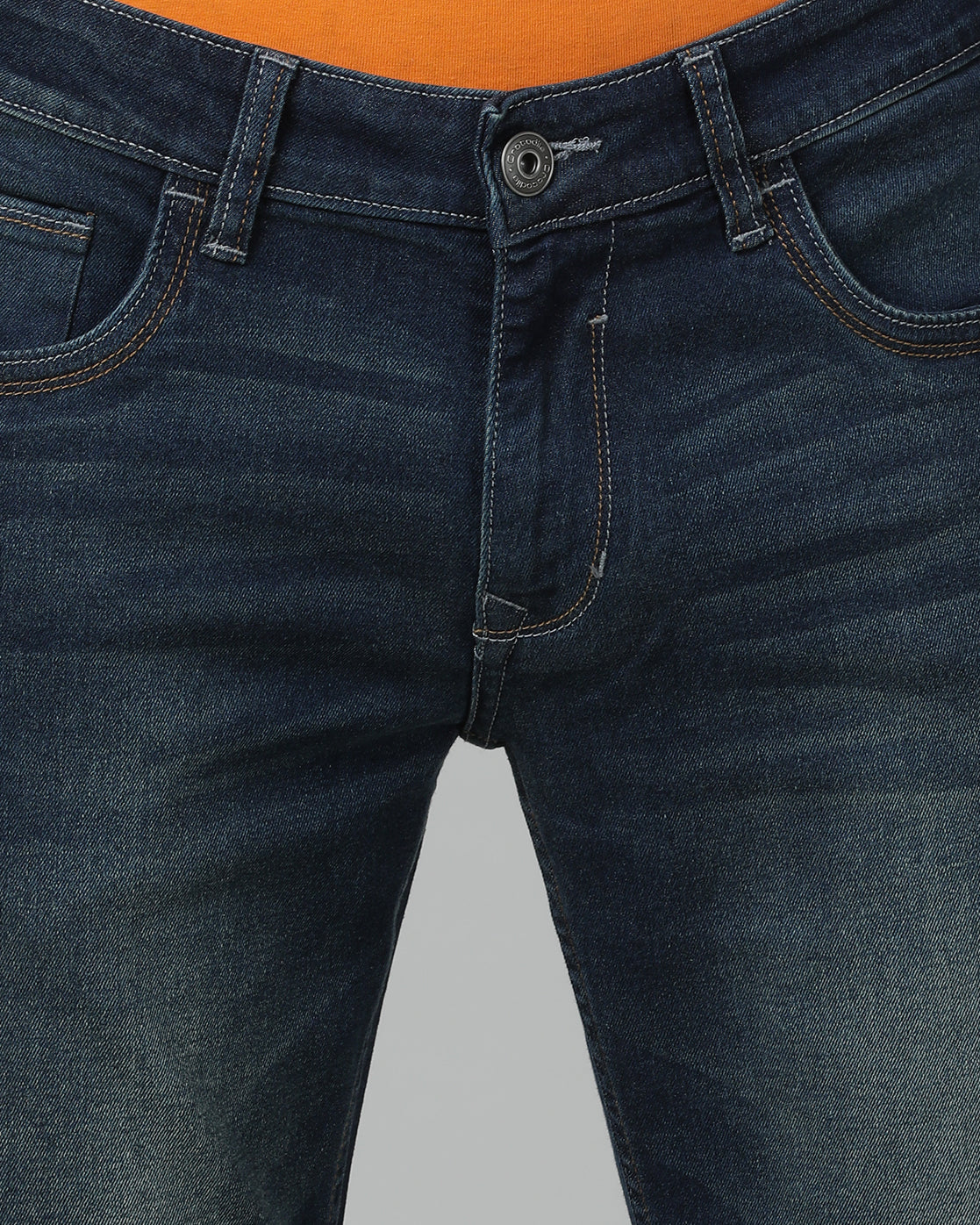 Man wearing a blue medium blue solid mid rise slim fit jean on a light gray background