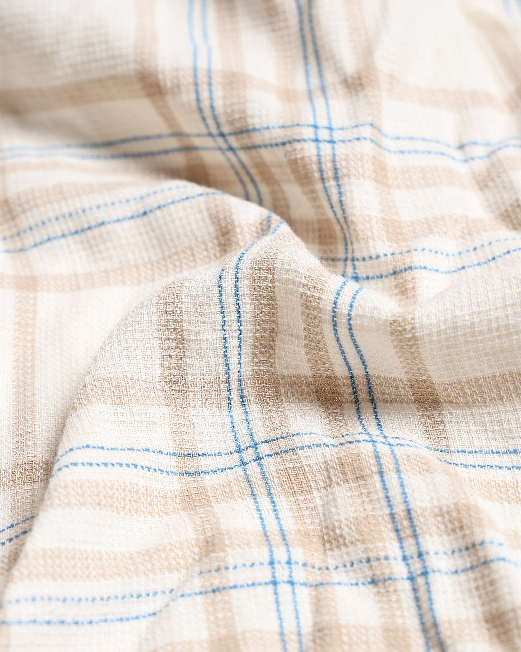 Close-up of checkered fabric with blue lines on a beige background