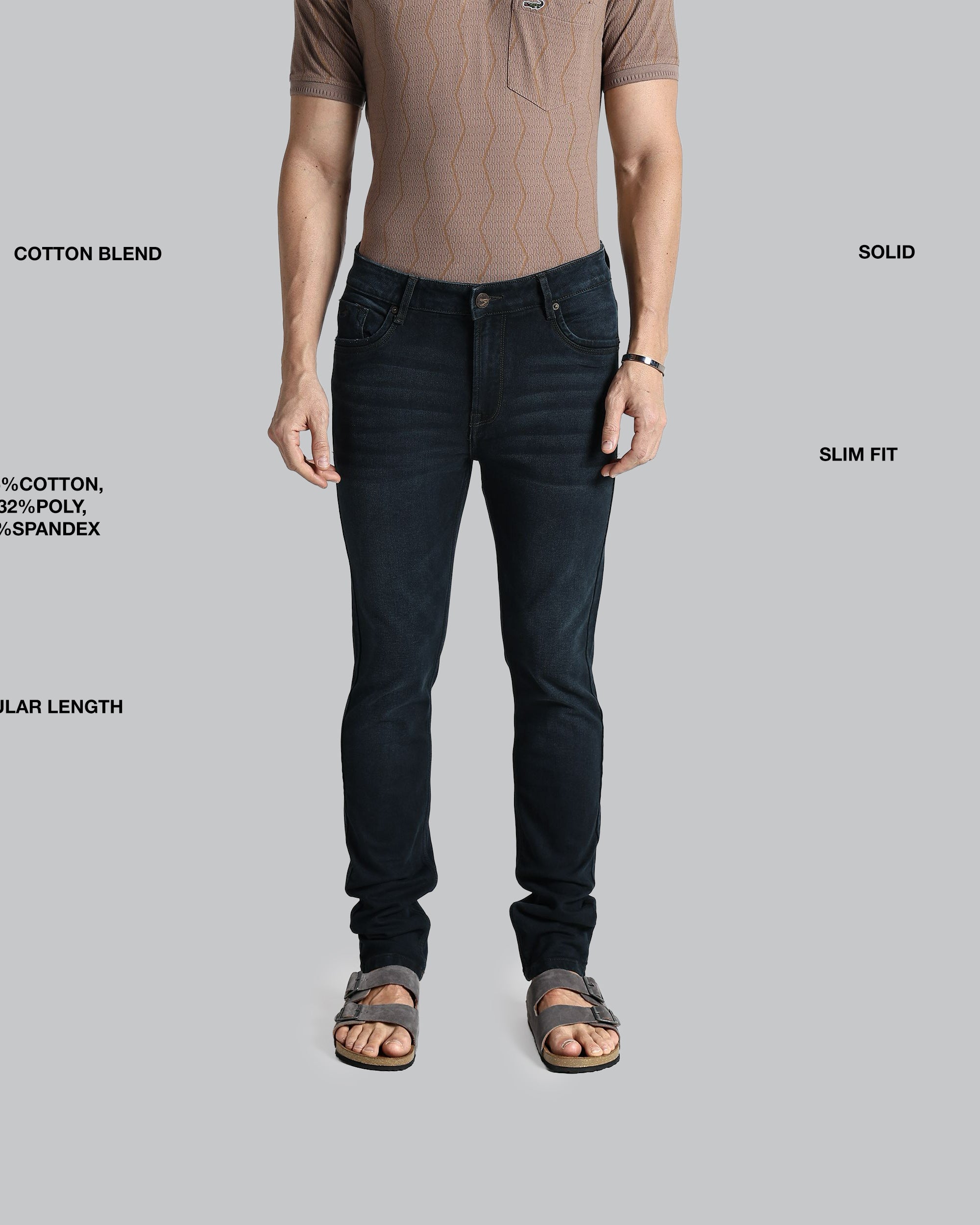 Man wearing black jeans with text detailing fabric composition, fit, and length on a gray background