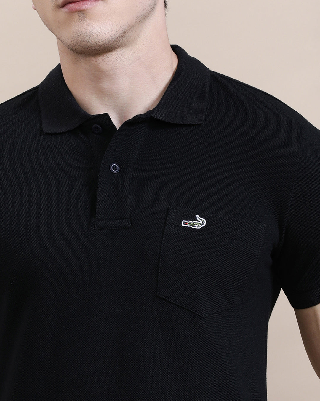 Man wearing a black casual solid black polo t shirt with pocket with casual styling on a gray background