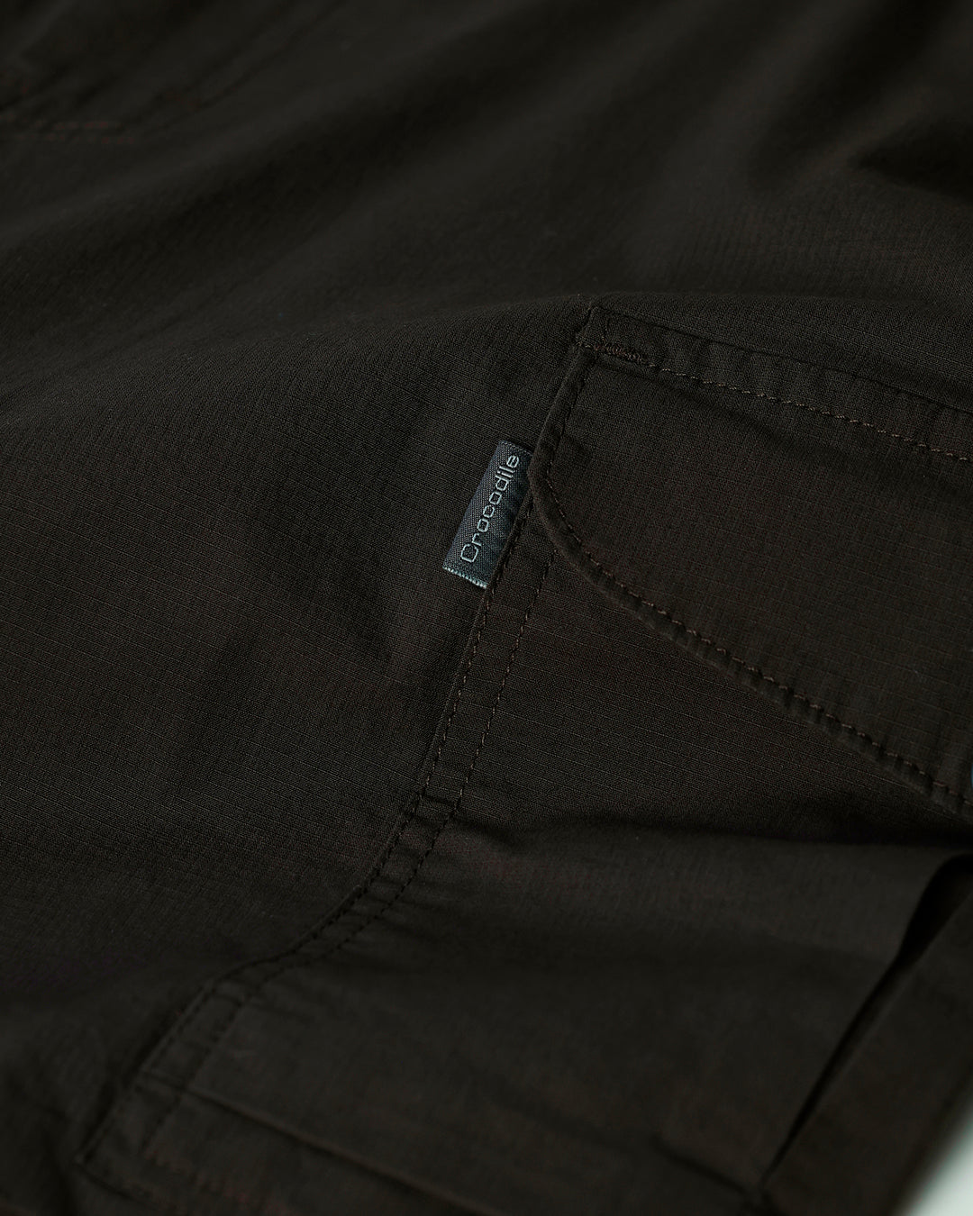 Man wearing a grey utility trekflex cargo pant in dark grey on a light gray background