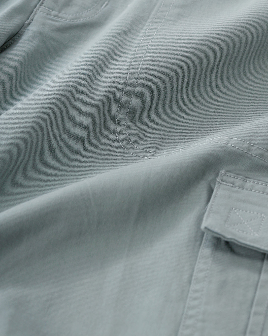 Man wearing a olive garment dyed cargo shorts in olive on a light gray background