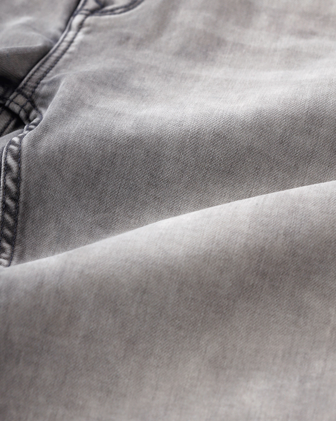 Man wearing a grey light grey knit slim fit jeans on a light gray background