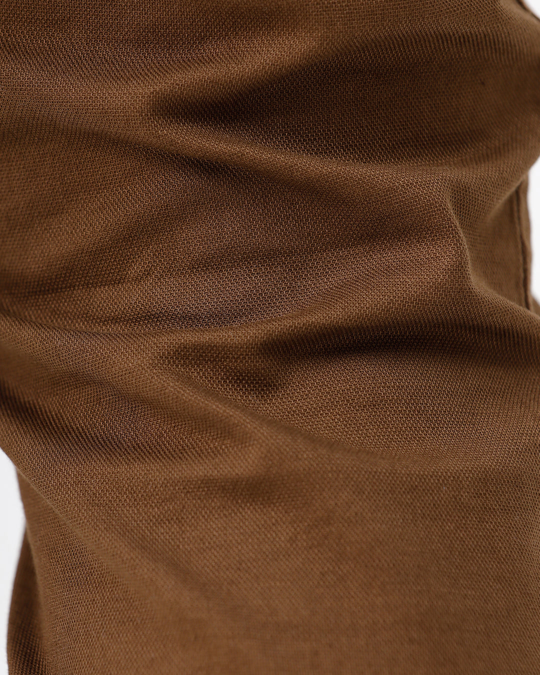 A man wearing brown slim-fit trousers, a cream and brown striped long-sleeve shirt, and brown suede loafers, standing against a plain white studio background.