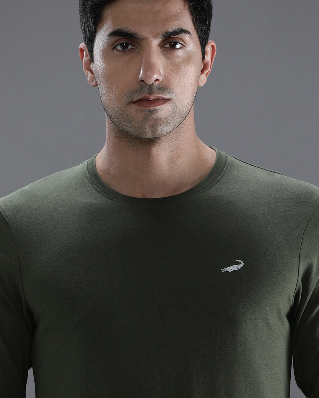 Man wearing a green solid green sport fit t shirt with casual styling on a gray background