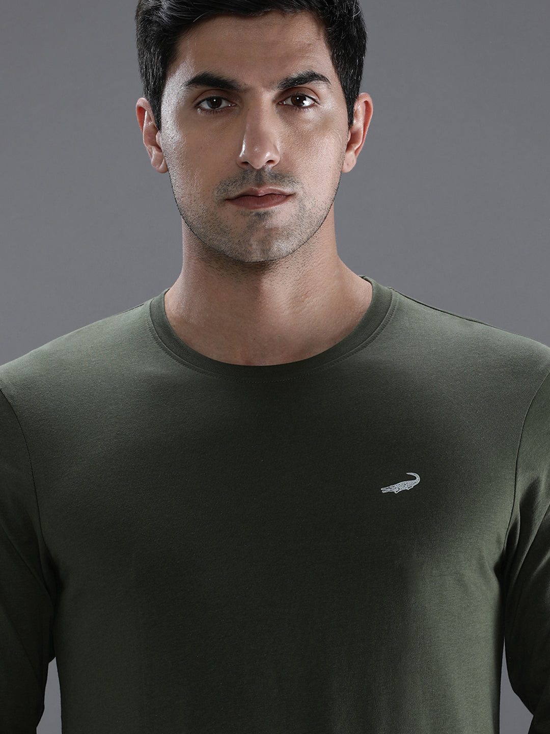 Man wearing a green solid green sport fit t shirt with casual styling on a gray background