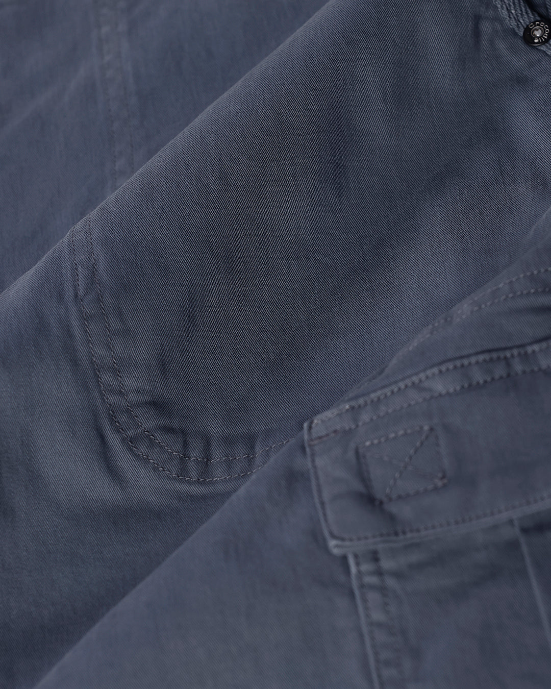 Man wearing a grey garment dyed cargo shorts in dark grey with casual styling on a gray background