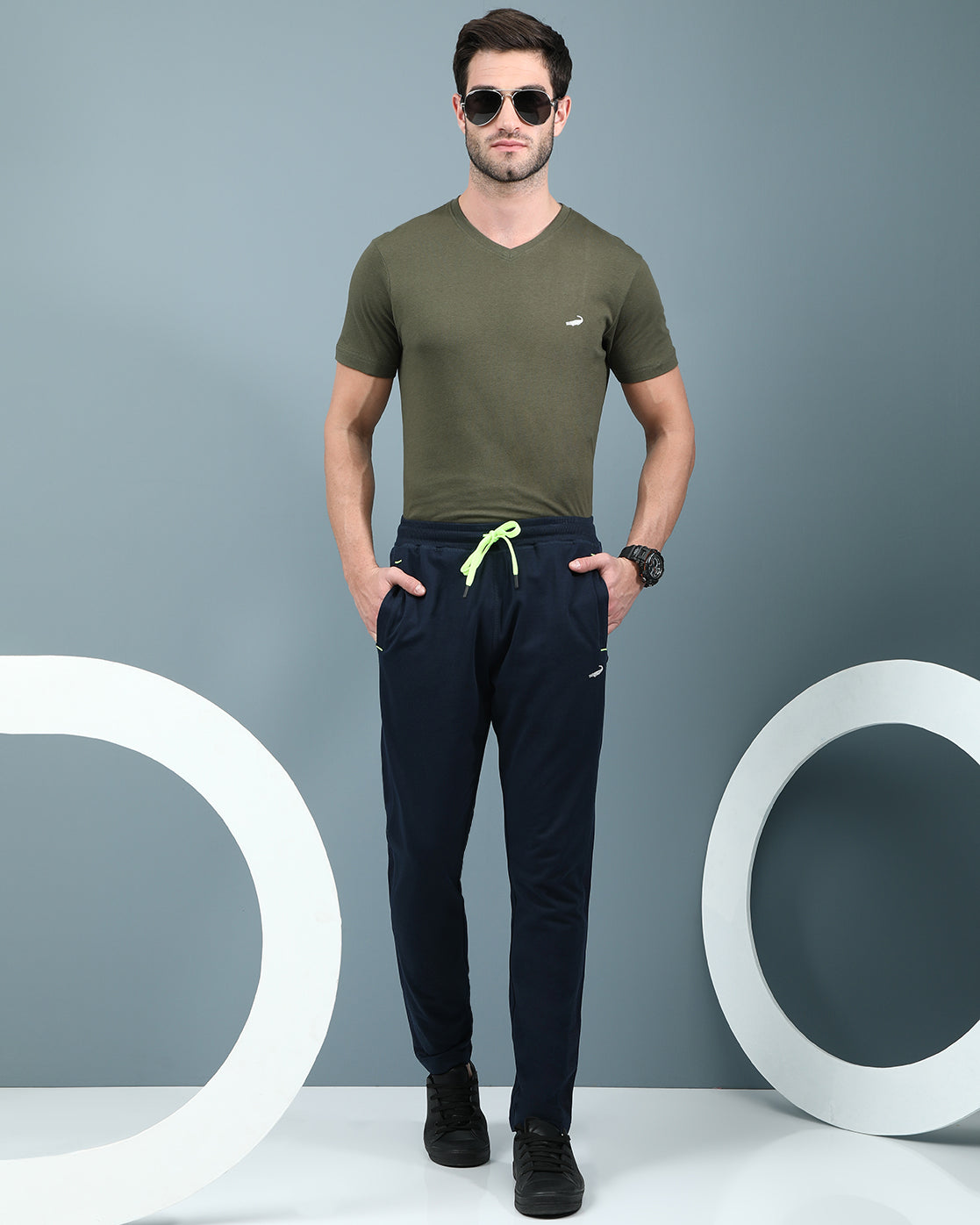 Man wearing a navy slim fit track pants in flexible navy on a light gray background