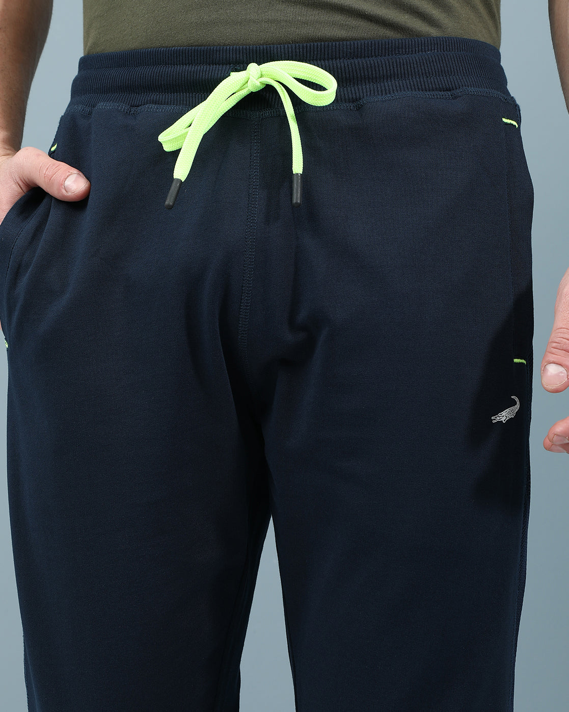 Man wearing a navy slim fit track pants in flexible navy on a light gray background