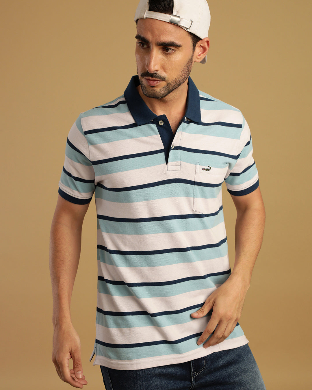 Man wearing a white blue and white striped polo t shirt with casual styling on a gray background