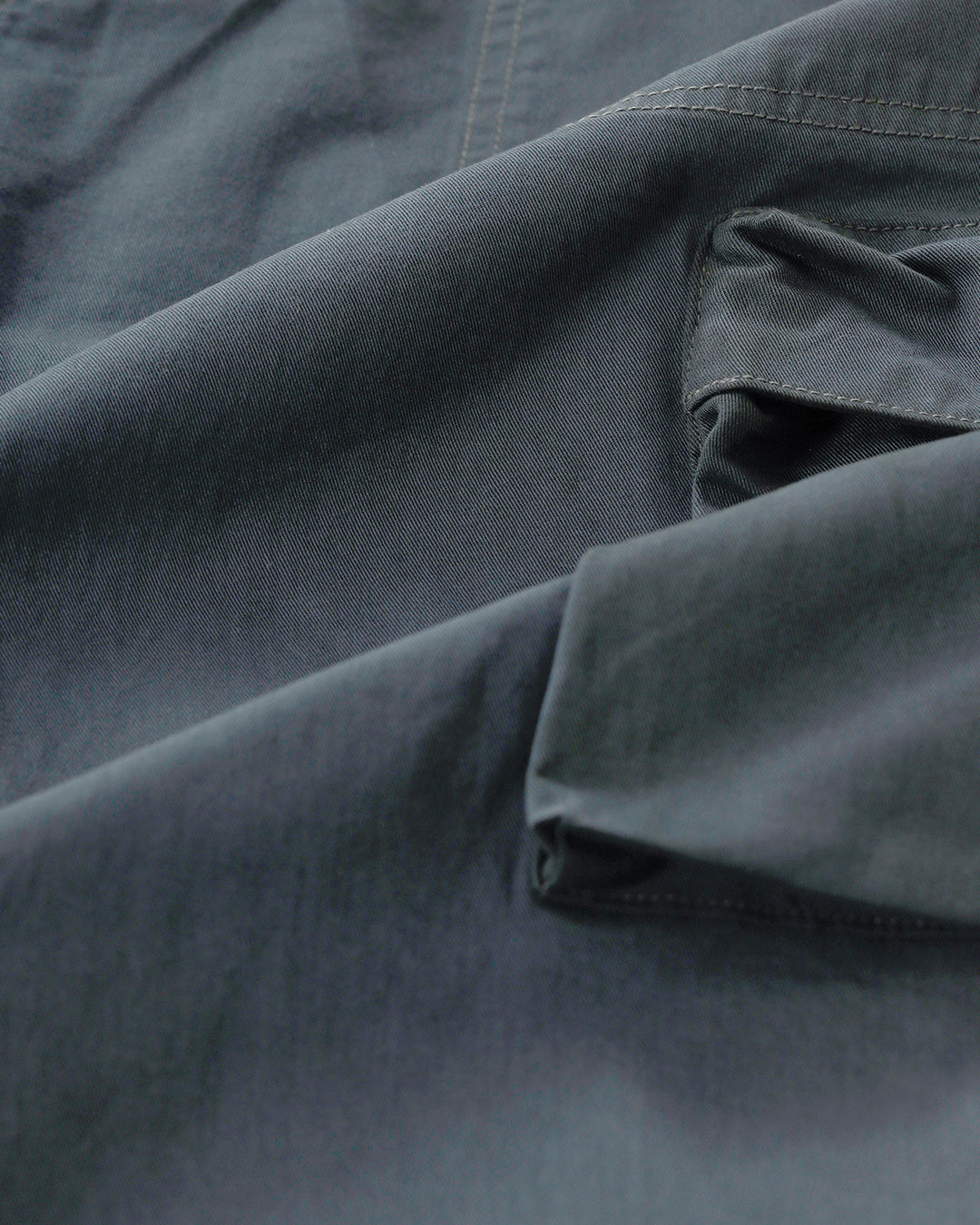 Man wearing a olive garment dyed cargo pant in olive with casual styling on a gray background