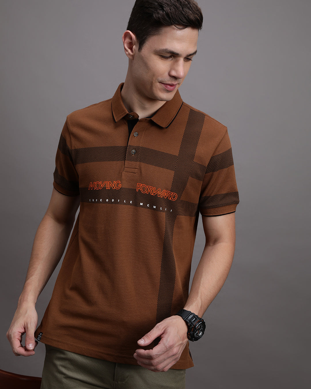 Man wearing a yellow rubber yellow printed polo t shirt with casual styling on a gray background