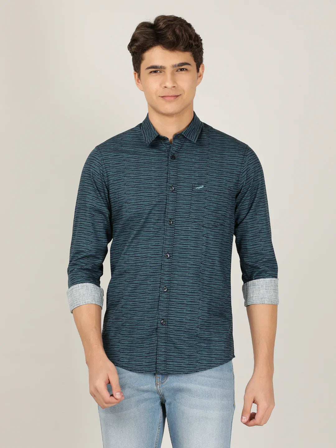 Man wearing a blue teal blue printed full sleeve 100% cotton casual shirt on a light gray background