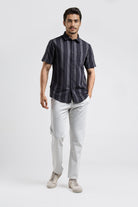 Man wearing a dark striped shirt and light pants on a white background