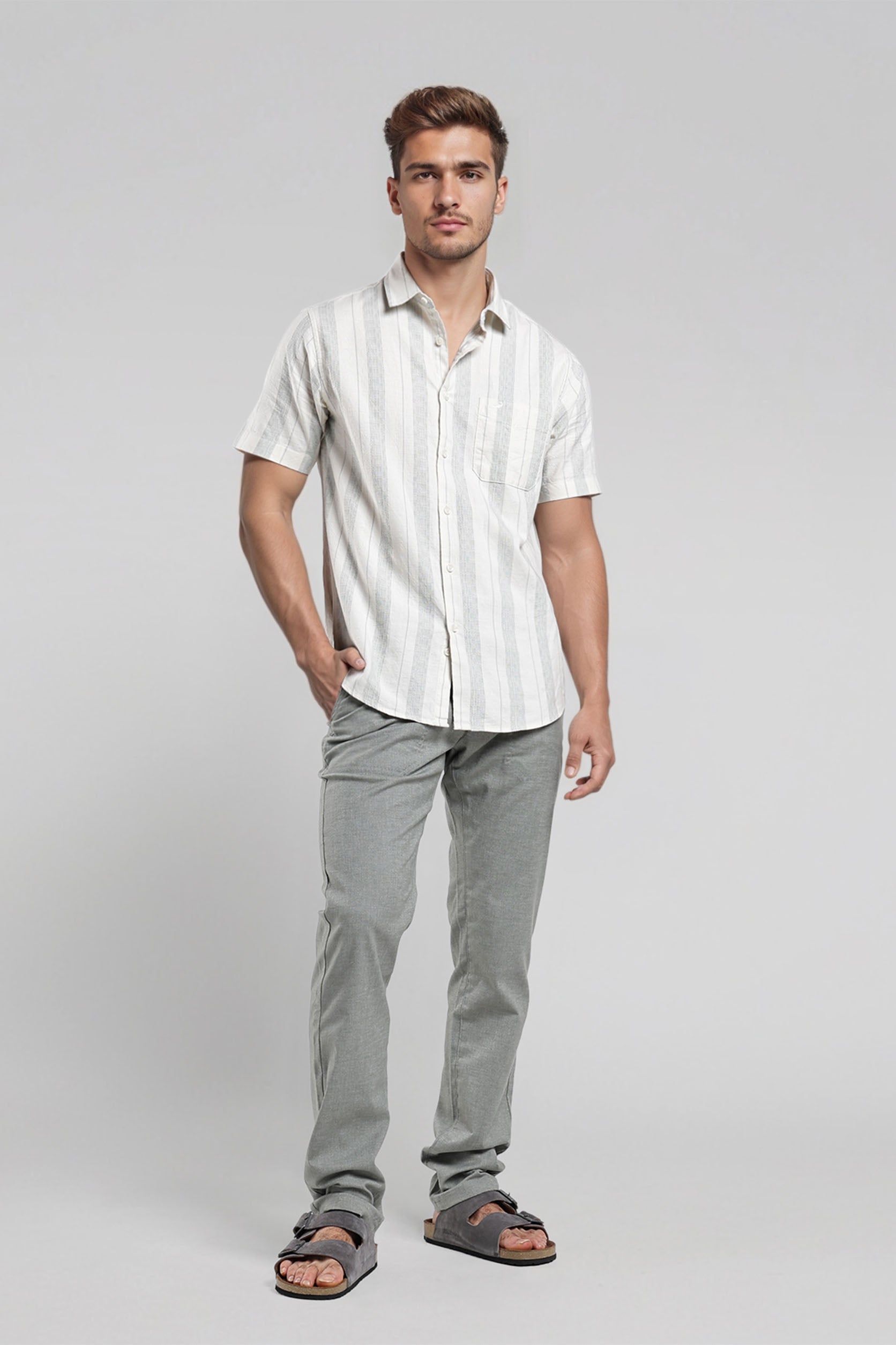 Man wearing a white striped shirt and gray pants on a light gray background