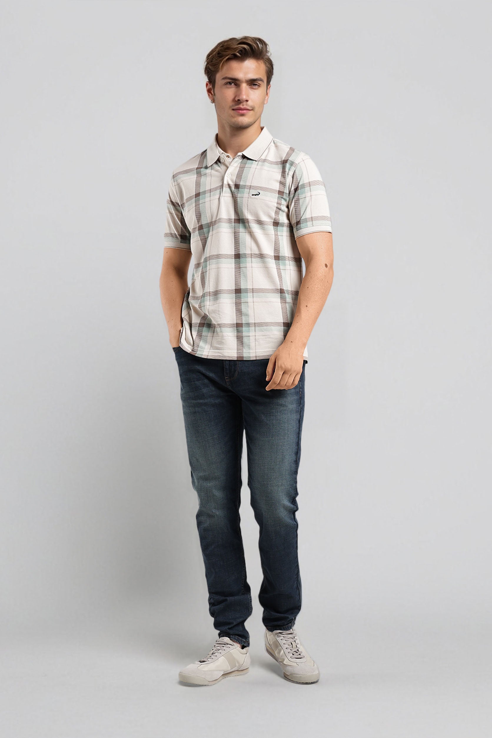 Man wearing a plaid shirt and jeans on a gray background