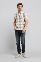 Man wearing a plaid shirt and jeans on a gray background