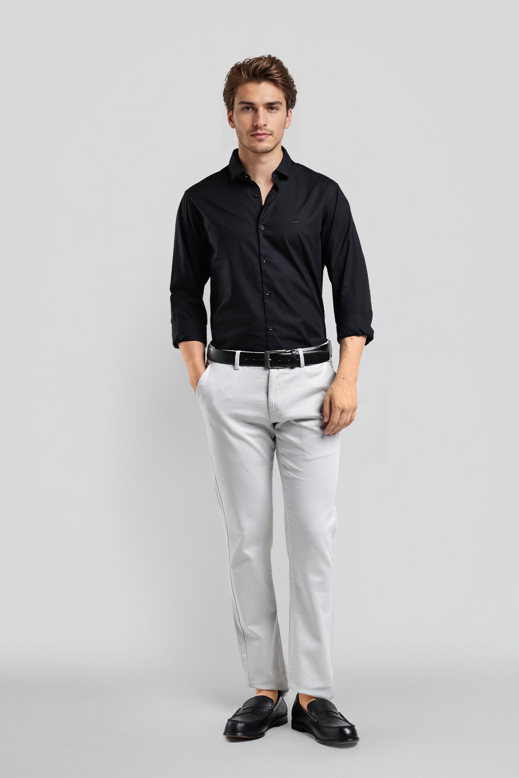 Man wearing a black shirt, white pants, and black shoes on a light gray background