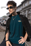 Man wearing a quad ripped over sized crew in teal with casual styling on a gray background