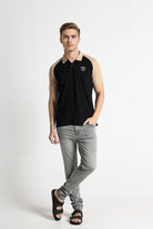 Man wearing a black and beige polo shirt with gray pants on a white background