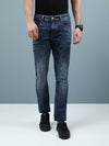 Man wearing a navy dark indigo navy solid mid rise slim fit jean on a light gray background