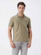 Man wearing a olive light olive structure comfort fit polo t shirt on a light gray background
