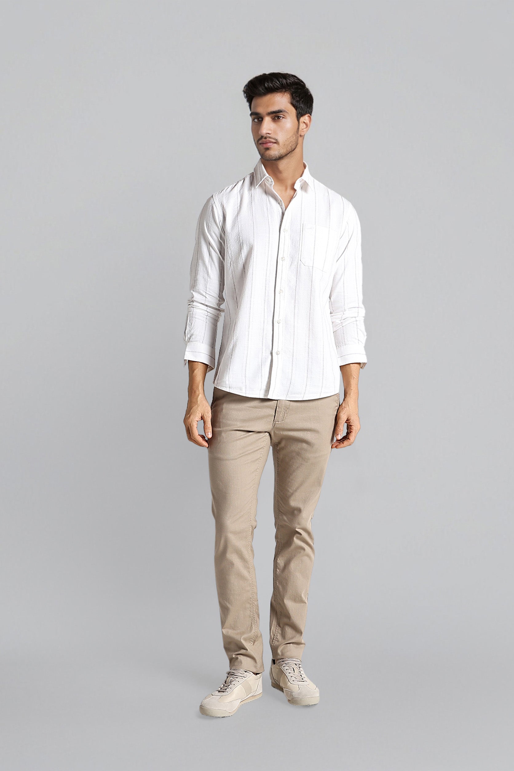 Man wearing a white shirt and beige pants on a gray background