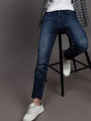 Man wearing a blue blue solid mid rise slim fit jean on a light gray background