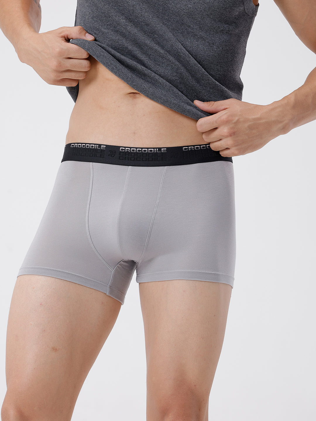 Person wearing gray boxer briefs with a visible brand logo on a plain background