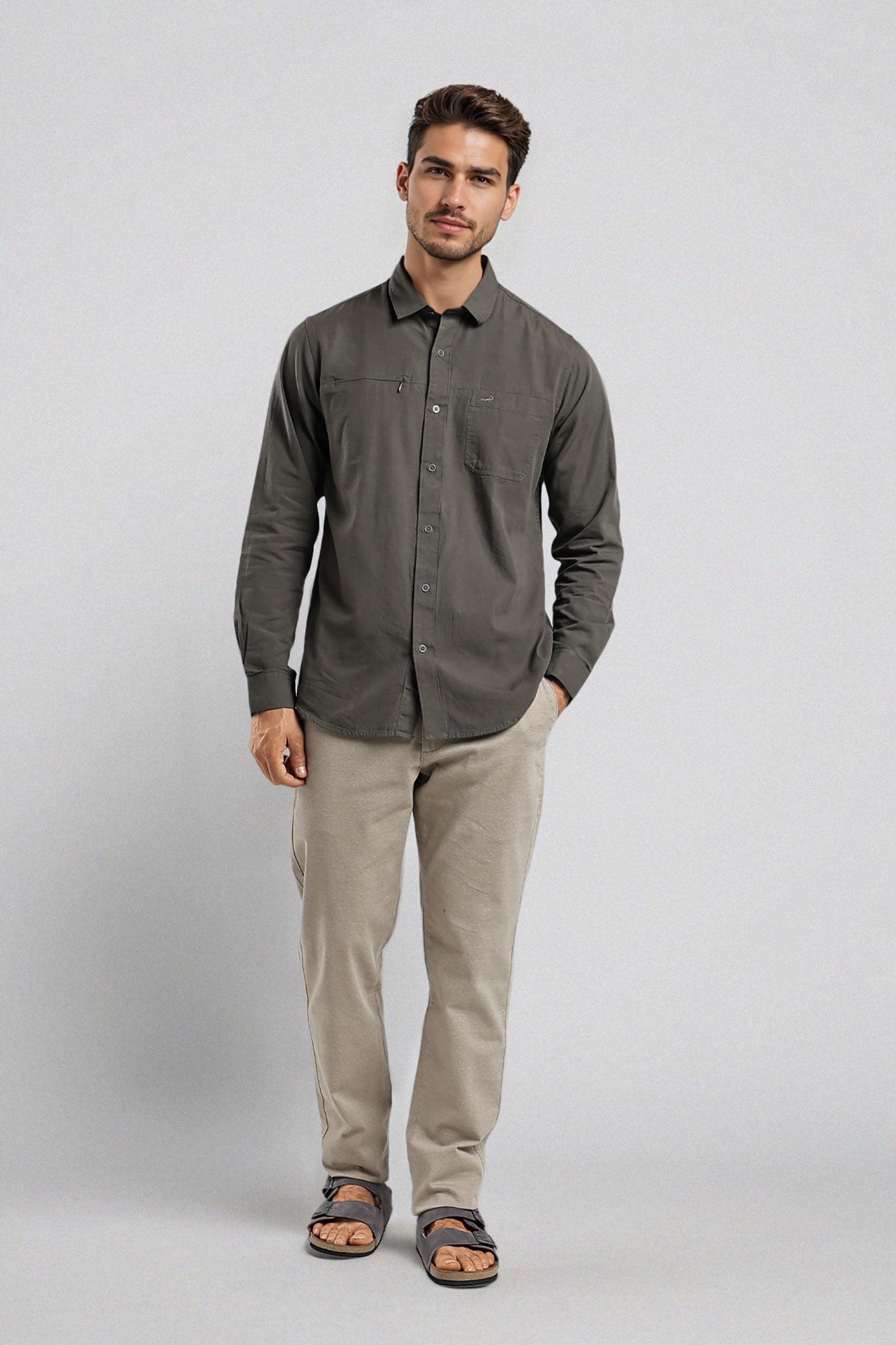 Man wearing a dark gray button-up shirt and beige pants on a light gray background