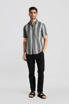 Man wearing a gray striped shirt and black pants on a light gray background