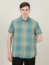Man wearing a green green checked half sleeve 100% cotton casual shirt with casual styling on a gray background