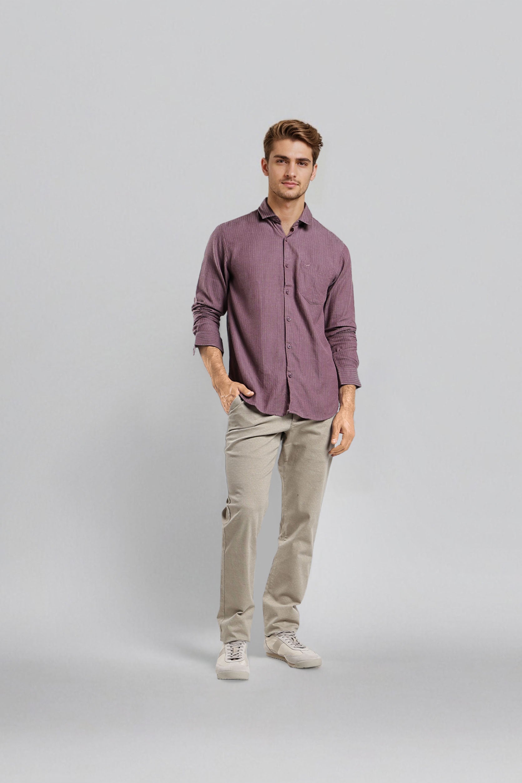 Man wearing a purple shirt and beige pants on a gray background