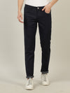 Man wearing a navy navy solid mid rise slim fit jean on a light gray background