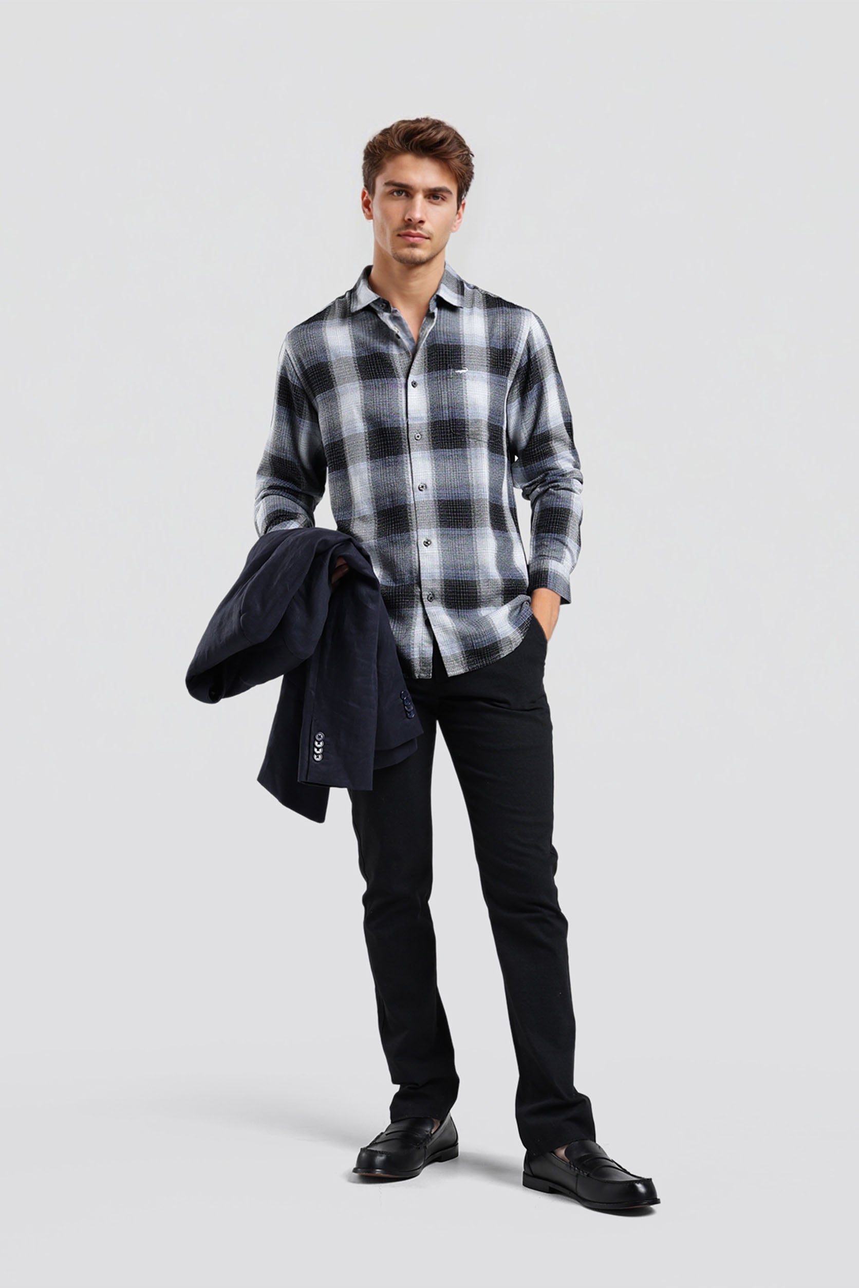 Man wearing a plaid shirt, black jacket, and black pants on a light gray background