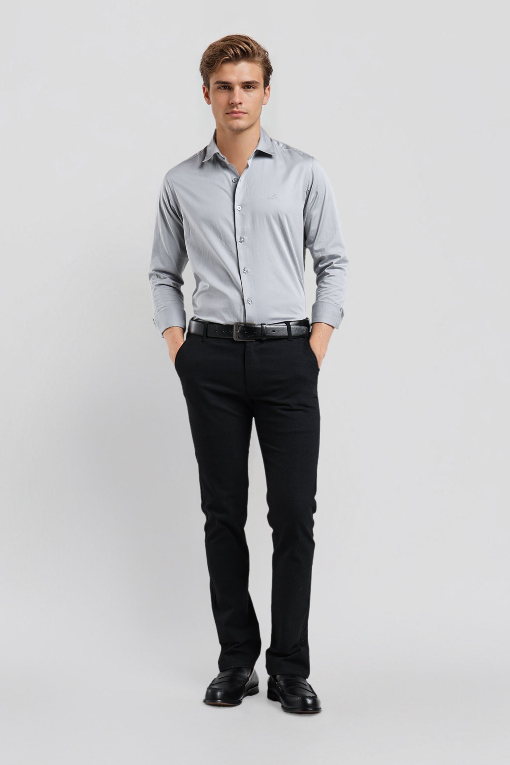 Man wearing a light gray dress shirt and black pants on a white background