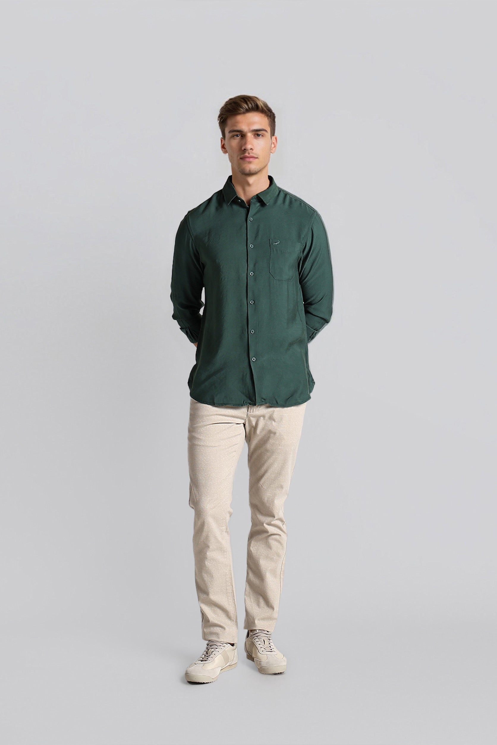 Man wearing a green shirt and beige pants on a gray background