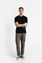 Man wearing a black t-shirt and green cargo pants on a white background
