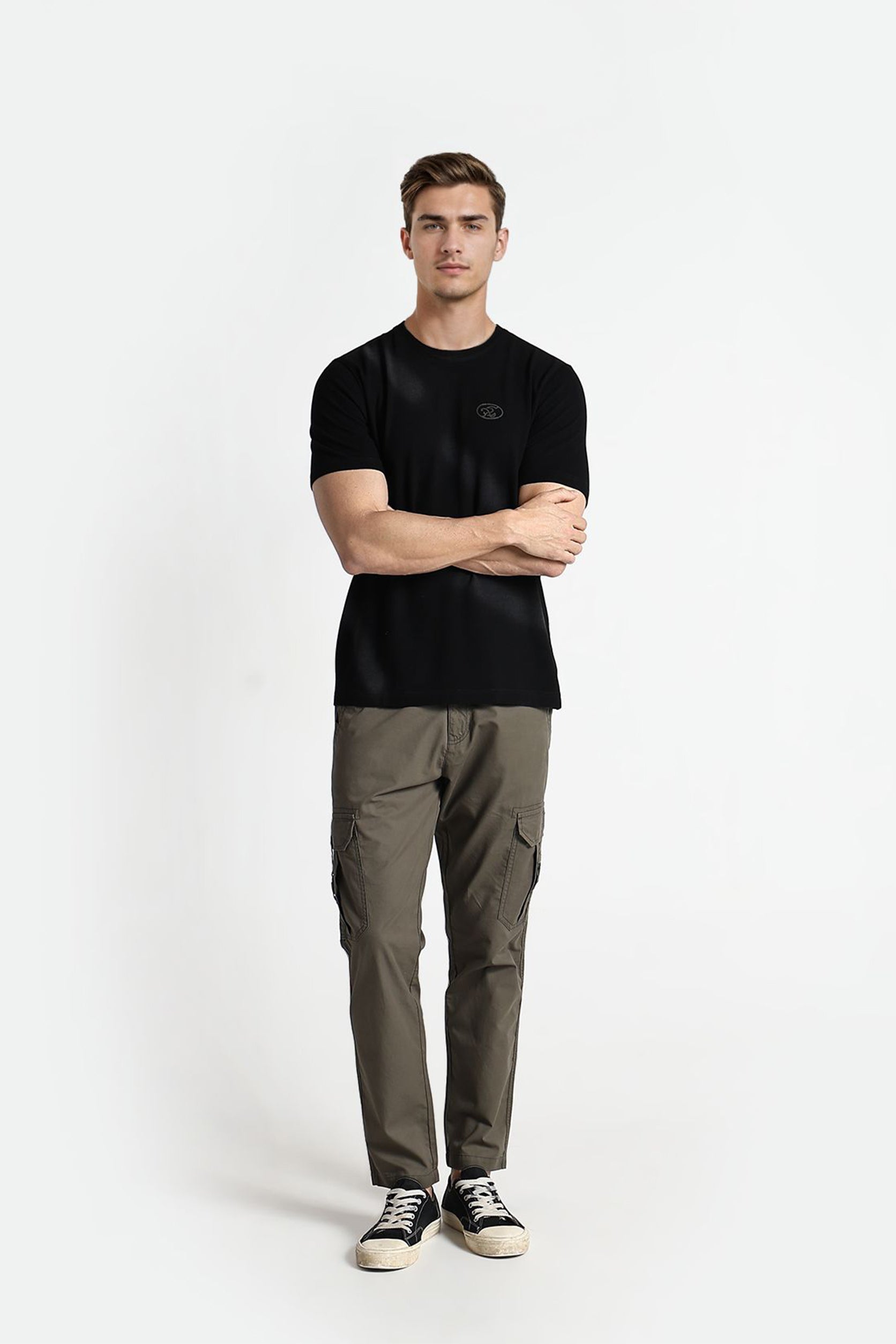 Man wearing a black t-shirt and green cargo pants on a white background