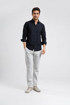 Man wearing a black shirt and light gray pants on a white background