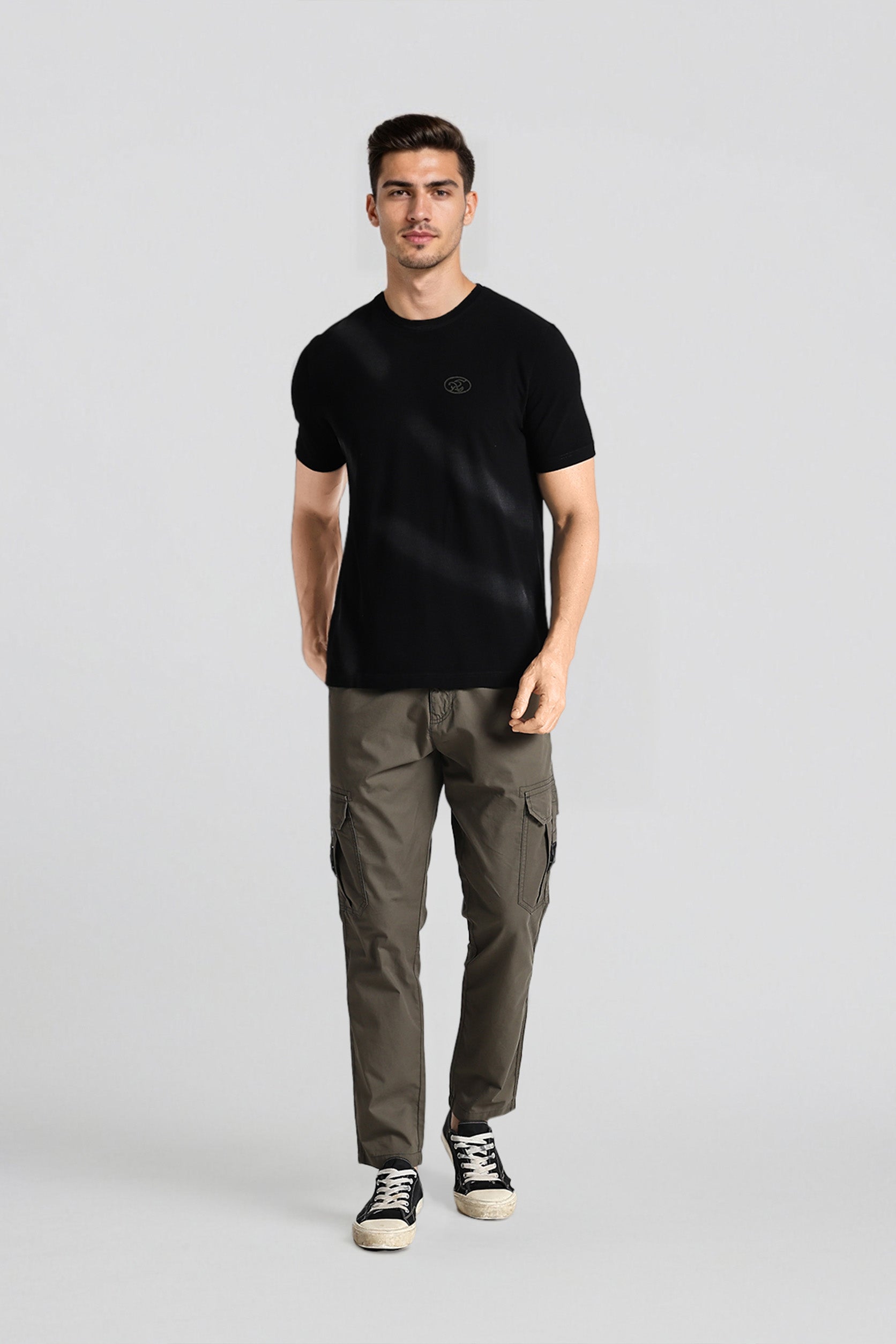 Man wearing a black t-shirt and green cargo pants on a white background