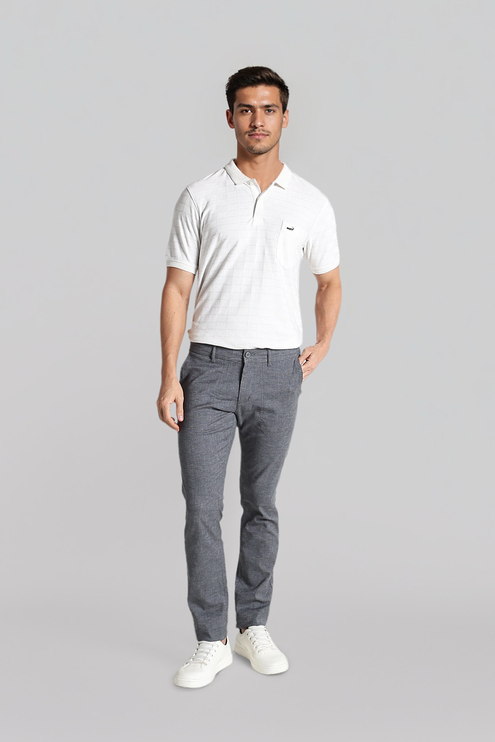 Man wearing a white polo shirt and gray pants on a gray background