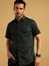 Man wearing a green printed green half sleeve shirt with casual styling on a gray background