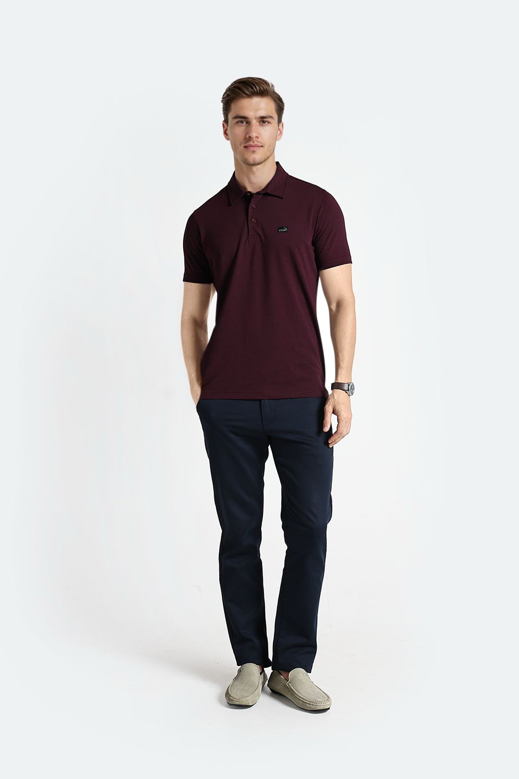 Man wearing a maroon polo shirt and dark pants on a white background