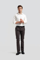 Man wearing a white shirt and dark pants on a light gray background