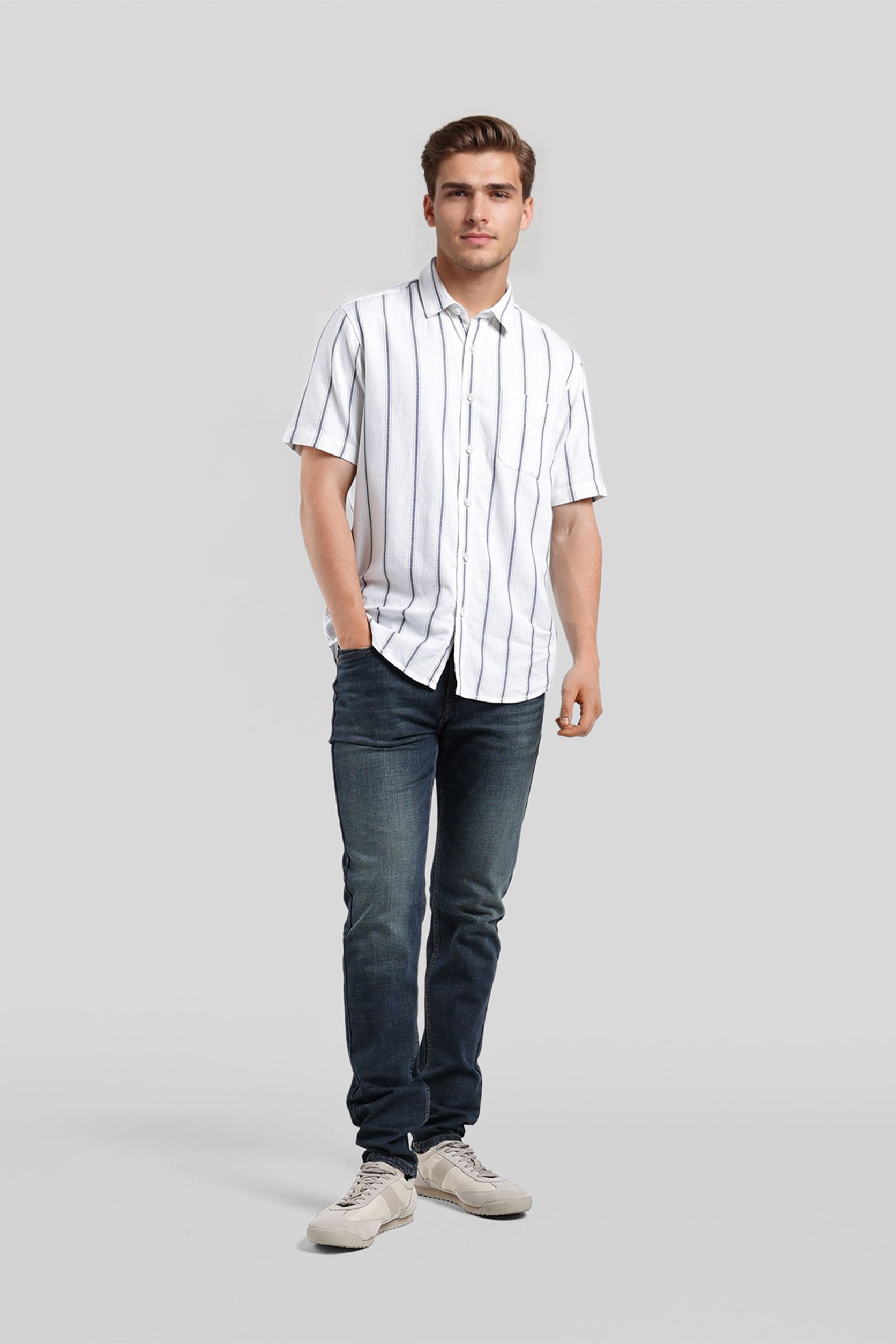 Man wearing a white striped shirt and blue jeans on a gray background