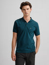 Man wearing a blue solid blue slim fit polo t shirt with casual styling on a gray background