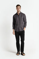 Man wearing a striped shirt and black pants on a white background