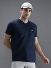 Man wearing a navy navy solid casual t shirt on a light gray background
