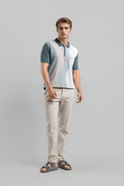 Man wearing a color-blocked polo shirt and beige pants on a gray background